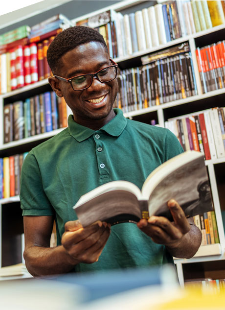 Young man reading a book in the library.