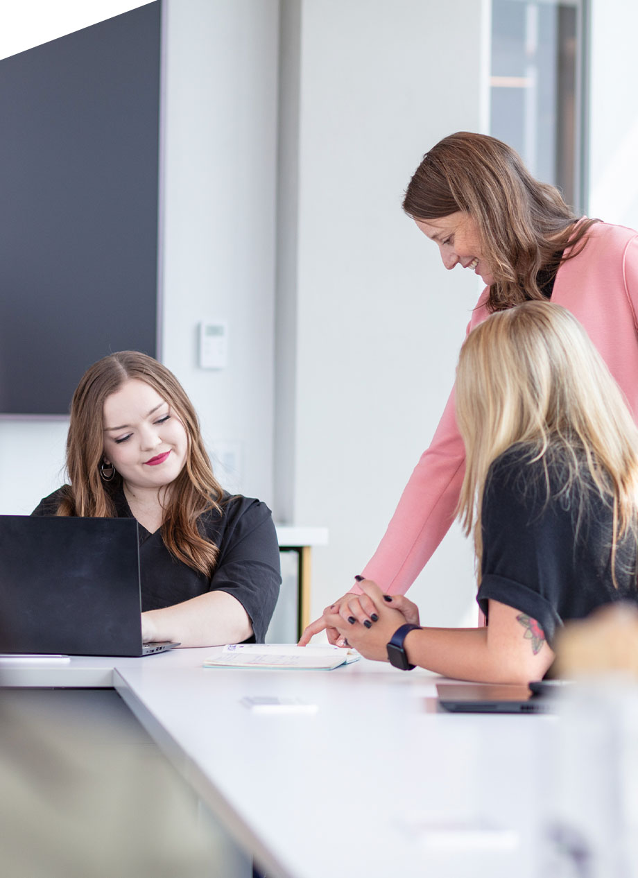 Three woman looking over documents in an office.