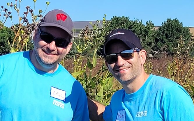 Two Ascendium employees outside on a sunny day standing in front of tall prairie grasses